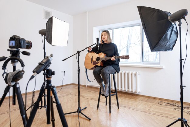 Uma jovem toca violão gravando vídeo e som