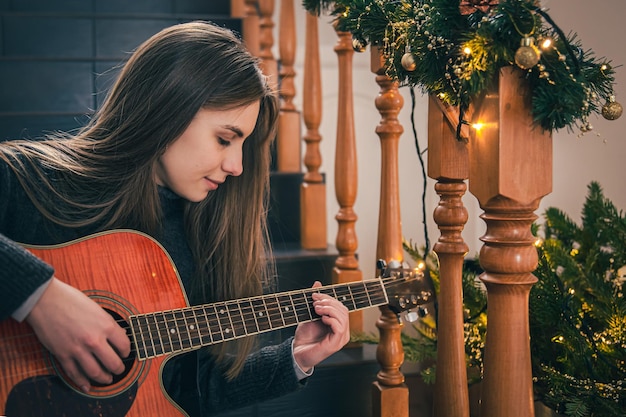 Uma jovem tocando violão sentado nos degraus em casa