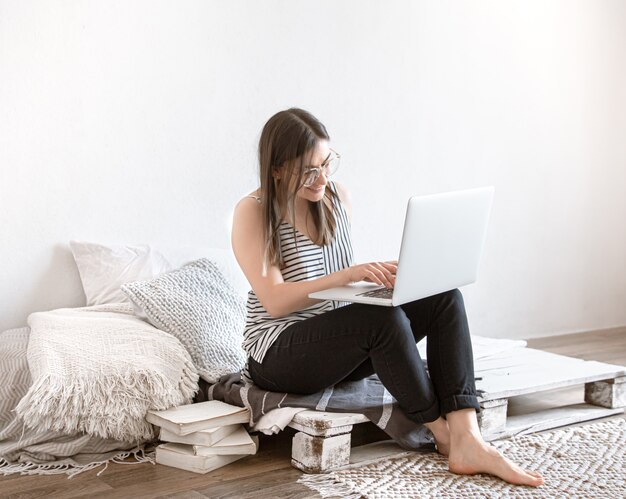 Uma jovem trabalha remotamente em um computador em casa. Freelancer e trabalho na Internet.