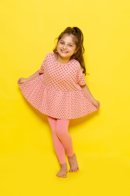 Uma linda criança de vestido rosa sorrindo e posando