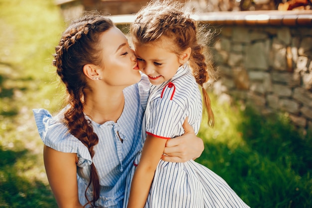 Uma linda e uma linda mãe de cabelos compridos em um vestido azul de pé em um parque solar e jogando