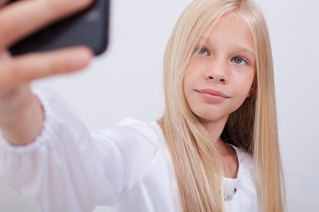 Uma linda garota adolescente tirando selfies com seu telefone inteligente