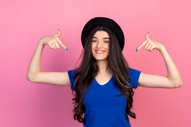Uma linda garota usando chapéu e apontando o dedo para si mesma foto de alta qualidade