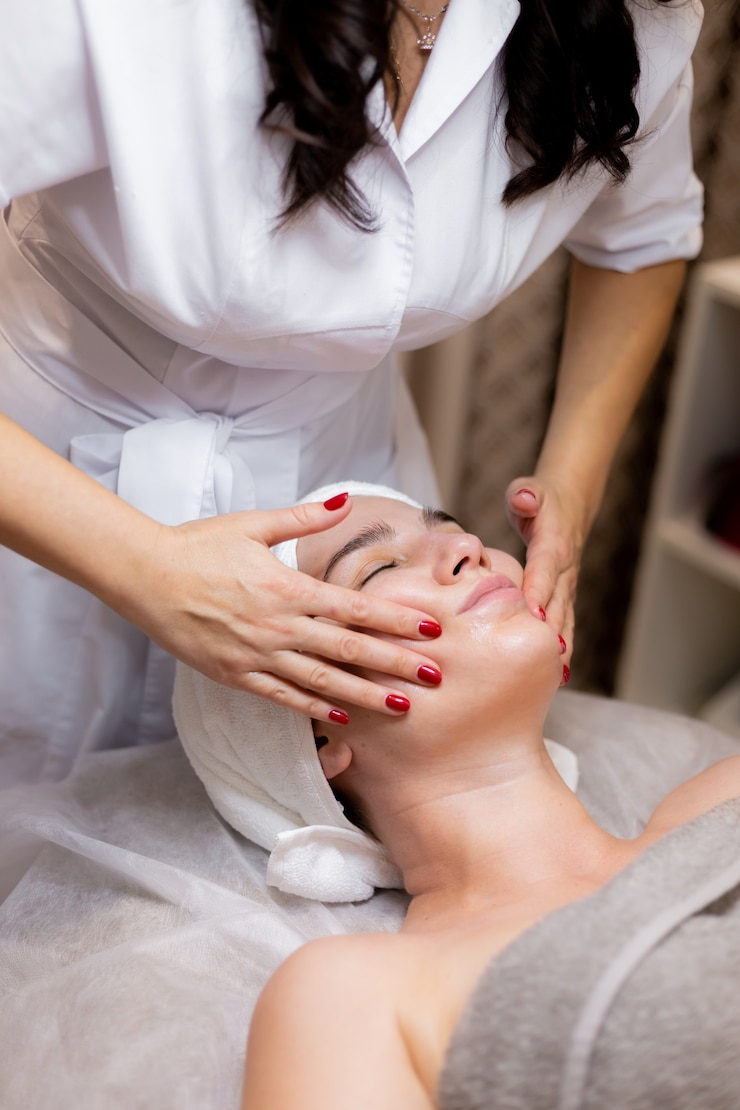 Foto grátis uma linda jovem deita-se na mesa da esteticista e recebe procedimentos, uma leve massagem facial.