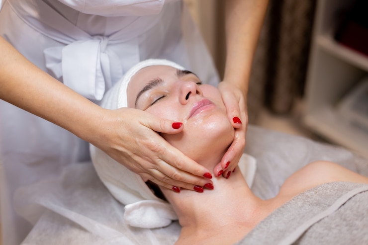 Foto grátis uma linda jovem deita-se na mesa da esteticista e recebe procedimentos, uma leve massagem facial.