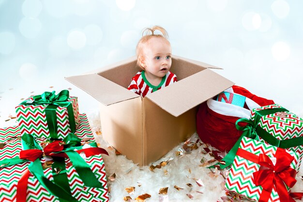 Uma linda menina de 1 ano sentada em uma caixa no natal