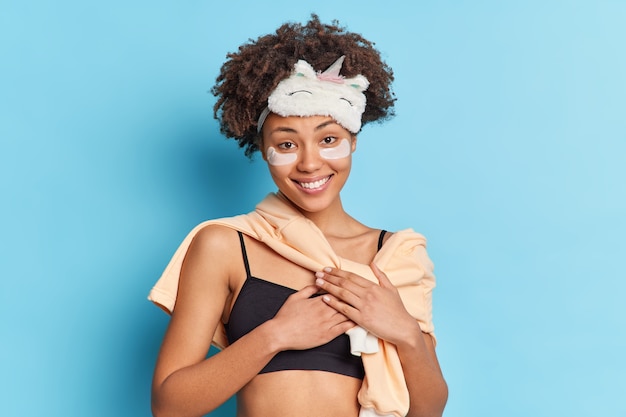 Uma linda mulher afro-americana com um sorriso suave aplica adesivos de colágeno sob os olhos para refrescar a pele