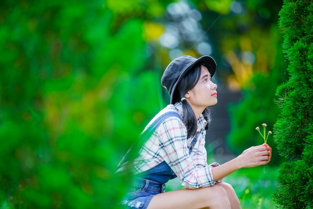 Uma linda mulher asiática usando um chapéu para relaxar e desfrutar no jardim verde como pano de fundo.