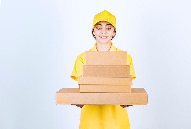 Uma linda mulher de uniforme amarelo segurando caixas de papel artesanal em branco.