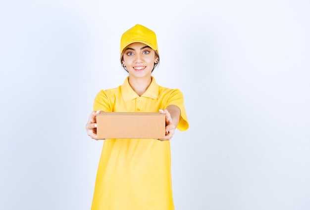 Uma linda mulher de uniforme amarelo segurando uma caixa de papel artesanal em branco.