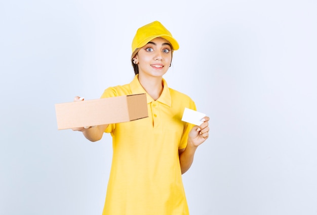 Uma linda mulher de uniforme amarelo segurando uma caixa de papel artesanal em branco.