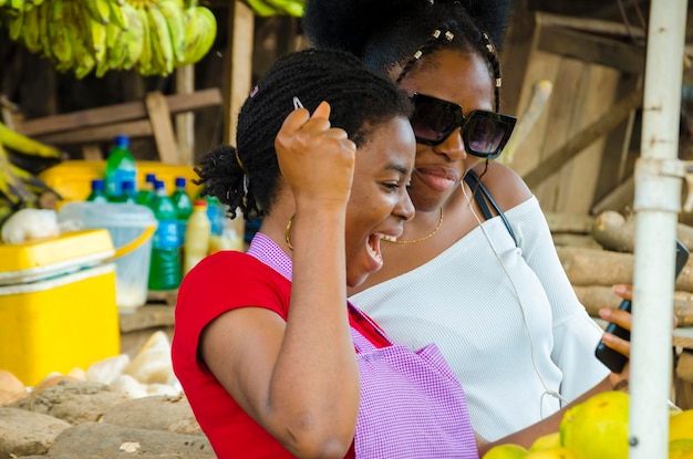 Uma linda mulher do mercado africano e seu cliente se sentindo surpresos com o que eles estão no celular