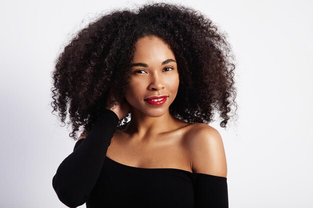 Uma linda mulher negra toca o cabelo encaracolado.