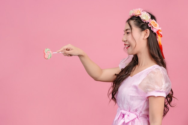 Uma linda mulher vestida com uma princesa rosa está brincando com seu doce doce em um rosa.