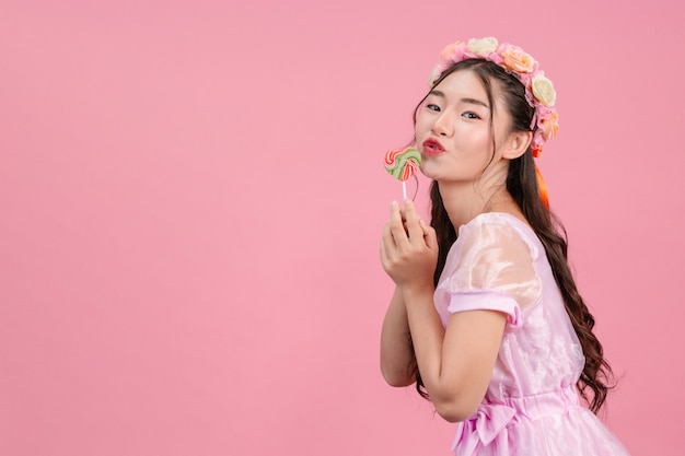 Uma linda mulher vestida com uma princesa rosa está brincando com seu doce doce em um rosa.