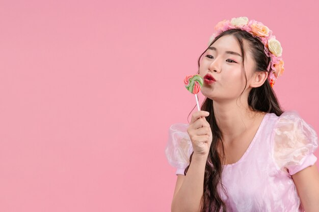 Uma linda mulher vestida com uma princesa rosa está brincando com seu doce doce em um rosa.