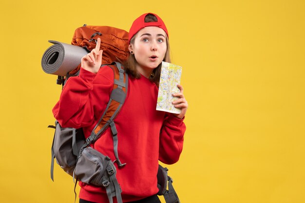Uma linda viajante feminina com uma mochila segurando um mapa apontando para o teto