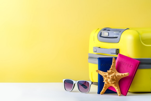 Uma mala de viagem amarela brilhante, passaporte, óculos de sol e estrela do mar. conceito de viagens. copyspace