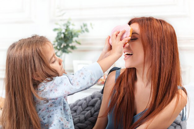 Uma menina bonitinha curtindo, brincando e criando com bolo com a mãe