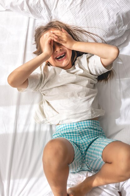 Foto grátis uma menina bonitinha deita na cama de manhã e sorri