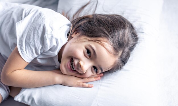 Uma menina bonitinha deita na cama e não quer se levantar