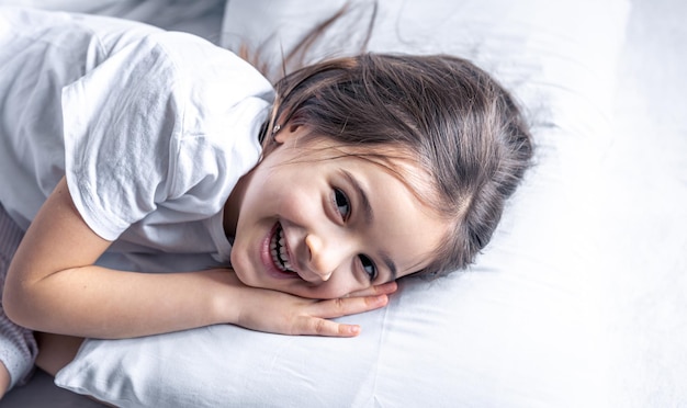 Uma menina bonitinha deita na cama e não quer se levantar