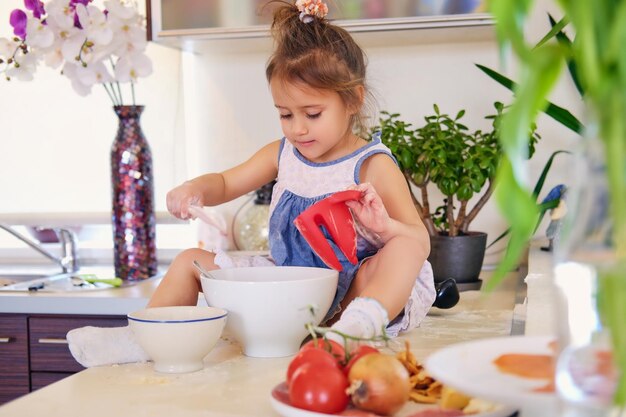 Uma menina bonitinha se senta em uma mesa na cozinha e tenta fazer mingau de dieta.