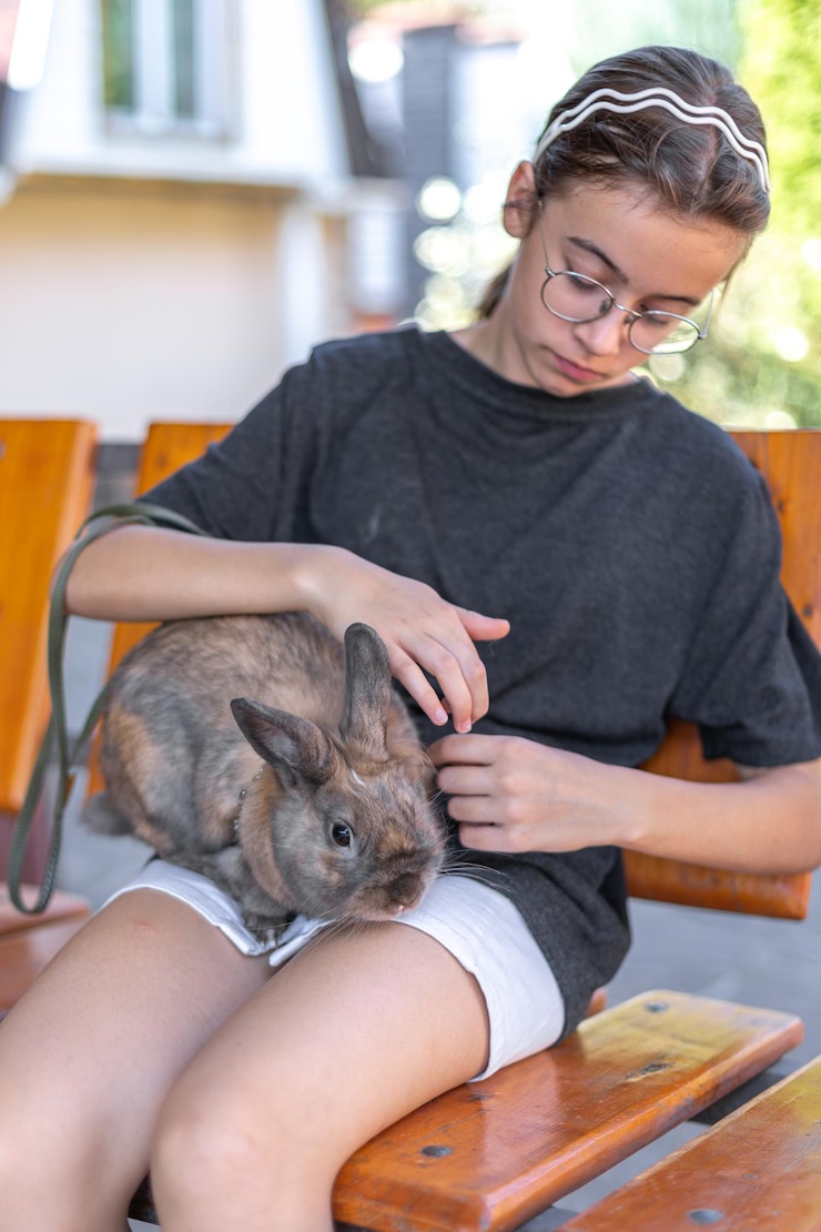 Foto grátis uma menina brinca com um coelho doméstico na rua conceito de animal de estimação