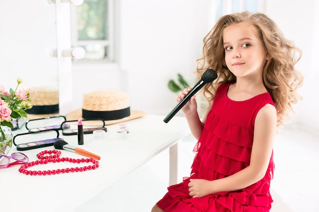 Uma menina com cosméticos, sentado perto do espelho.