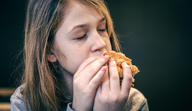 Uma menina com sardas come um hambúrguer