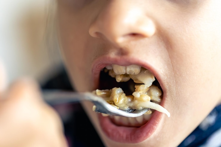 Foto grátis uma menina come mingau com frutas em close-up