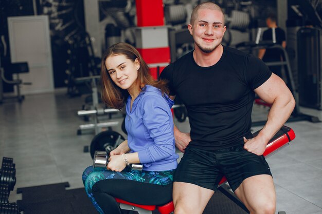 Uma menina jovem e bonita com o namorado dela treinando em um ginásio