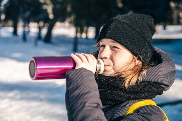 Foto grátis uma menina lá fora com uma garrafa térmica em um dia frio de inverno