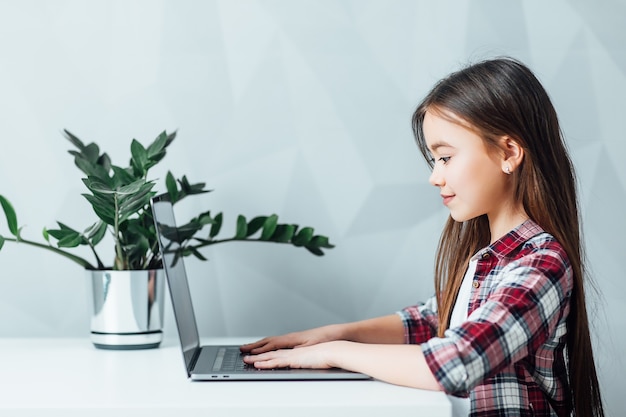 Uma menina sentada à mesa usando um tablet moderno