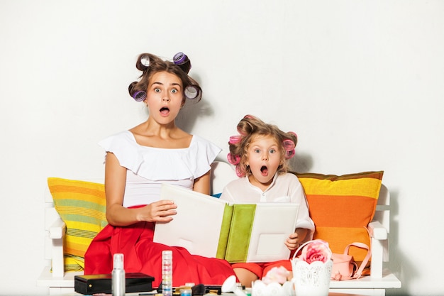 Uma menina sentada com a mãe e olhando para um álbum de fotos