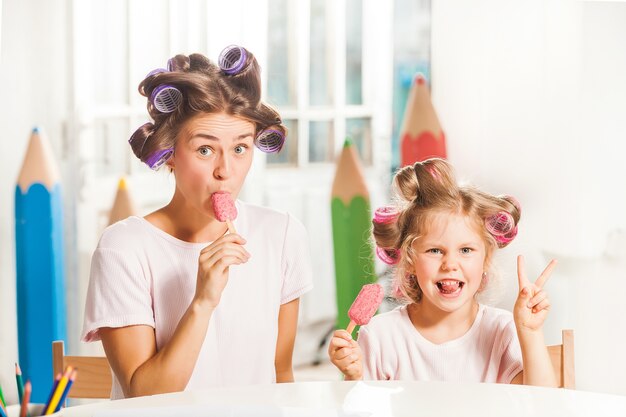 Uma menina sentada com a mãe tomando sorvete