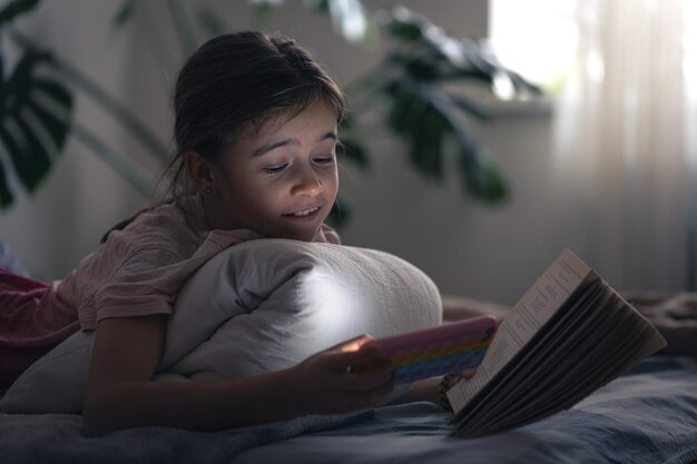 Uma menina usa o telefone segurando um livro nas mãos