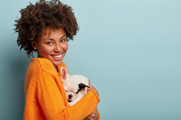 Foto grátis uma mulher afro-americana com um suéter laranja segurando um cachorro