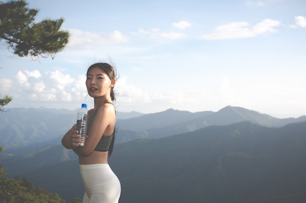 Uma mulher asiática bonita que meditating e que exercita na parte superior da montanha.