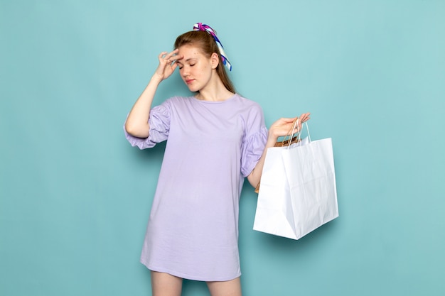 Uma mulher atraente, de frente, em vestido de camisa azul, segurando pacotes de compras em azul