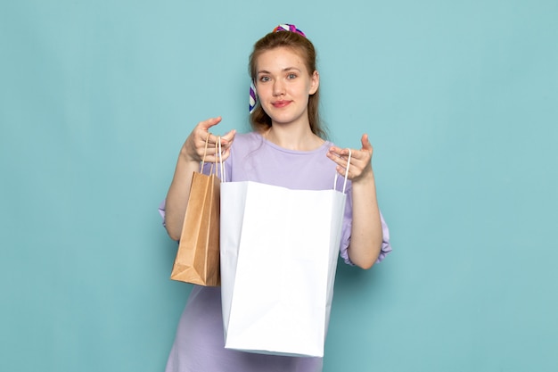 Uma mulher atraente, de frente, em vestido de camisa azul, segurando pacotes de compras em azul