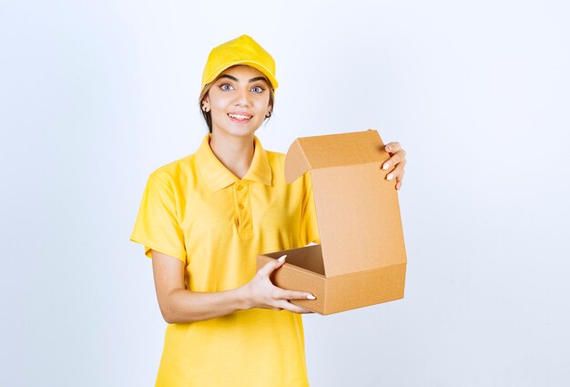 Uma mulher bonita em uniforme amarelo segurando uma caixa de papel artesanal em branco marrom aberta.