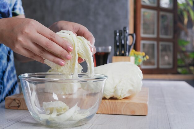 Uma mulher bonita está cortando vegetais na cozinha em casa.