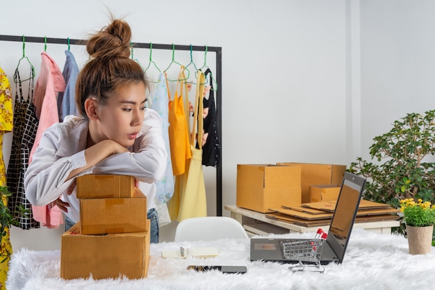 Uma mulher de negócios está trabalhando on-line e tentando responder à embalagem do cliente em casa na parede.