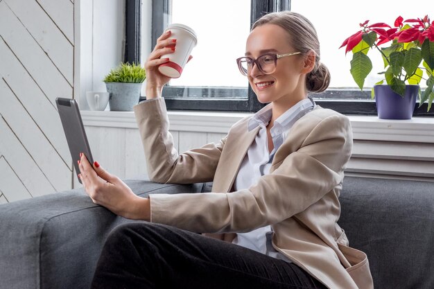 Uma mulher de óculos de sol trabalhando com computador tablet em casa.