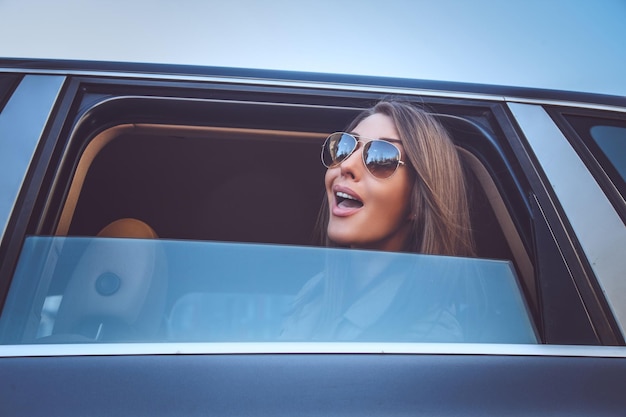 Uma mulher de óculos escuros olhando pela janela do carro.