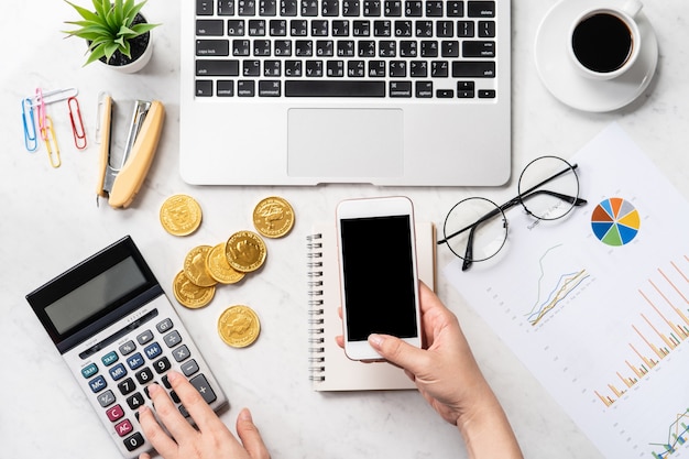 Uma mulher está calculando a taxa, o lucro e fazendo um pagamento online em uma mesa de escritório de mármore moderna, simulação, vista de cima, espaço de cópia, configuração plana