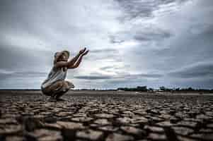 Foto grátis uma mulher está sentada pedindo chuva na estação seca, aquecimento global