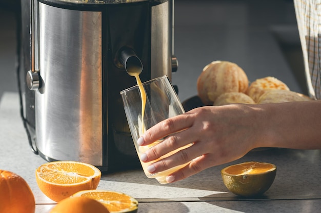 Foto grátis uma mulher faz suco de laranja em casa na cozinha com um espetador elétrico