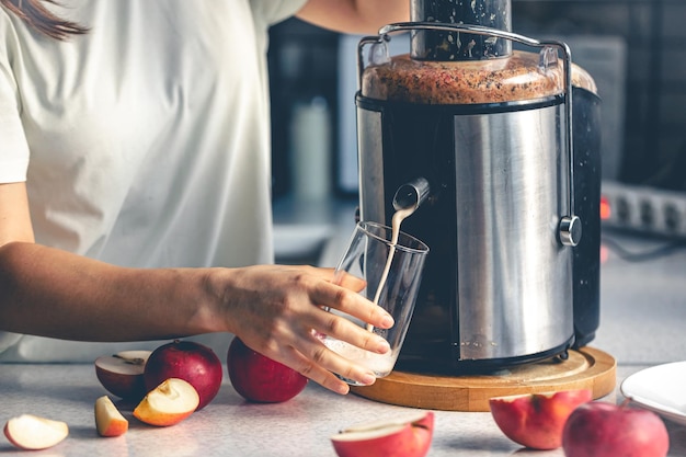 Foto grátis uma mulher faz suco de maçã em casa com um espremedor